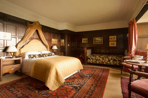 A grand retreat bedroom with carved wood panelling, a draped bed and period furnishings